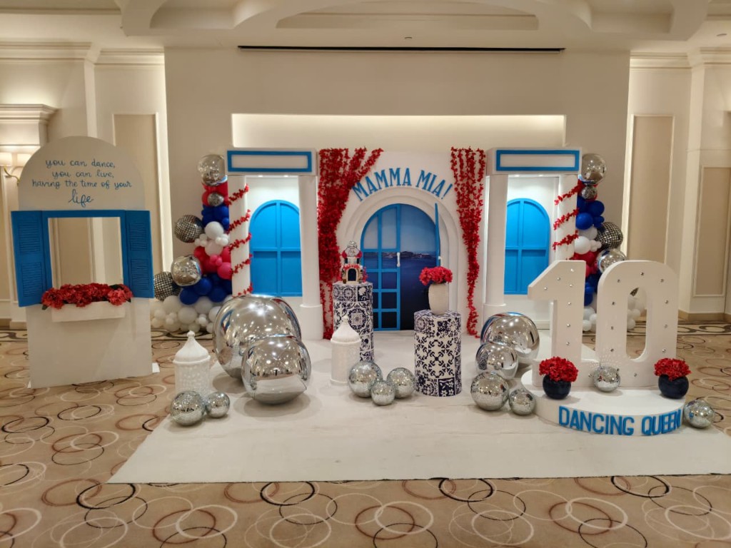 Mama Mia themed birthday backdrop with blue doors, red flowers and disco balls in Duhail, Qatar